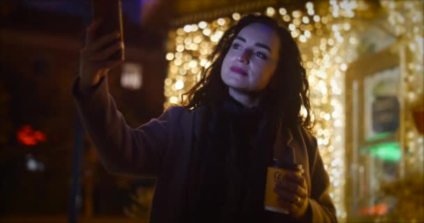 Atraktivní žena dělá selfie na pozadí Slavnostní rozsvícení noční město. — Stock video