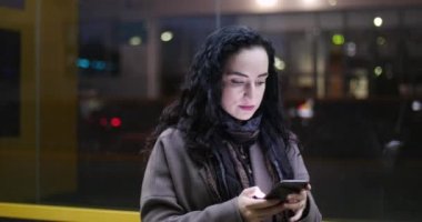 Çekici kadın şenlikli ışıklar gece şehrin arka plan üzerinde sokaklarda yürürken cep telefonunuzun.