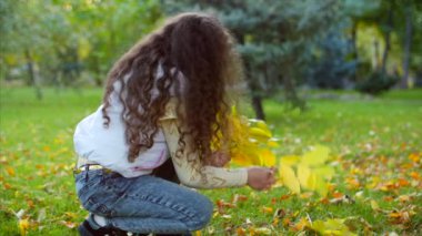 Moda mutlu gülümseyen şık neşeli Avrupa küçük sevimli kız güzel bir beyaz ceket yelek ve uzun sarışın kıvırcık saç yürür Sonbahar Park sahiptir mutlu oynarken ile sonbahar yaprakları, çalışan