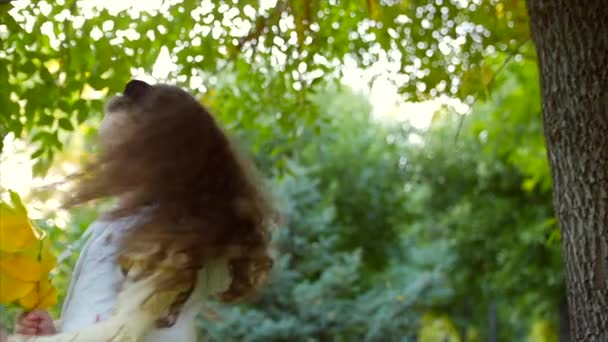 美丽时尚快乐微笑时尚愉快的欧洲小可爱的女孩在白色夹克背心和长金发卷发走在秋季公园享受愉快地玩秋叶, 运行 — 图库视频影像
