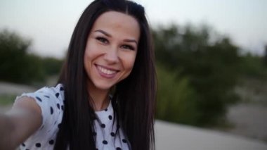 Güzel mutlu gülümseyerek şık neşeli Avrupa sevimli genç kız elinde beyaz bluz ve uzun karanlık pürüzsüz Well-Groomed saç Holding ile onun sevgili çalışan yalınayak üzerinde kum mutlu kadın Holding