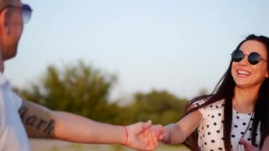 Güzel mutlu gülümseyerek şık neşeli Avrupa sevimli genç kız elinde beyaz bluz ve uzun karanlık pürüzsüz Well-Groomed saç Holding ile onun sevgili çalışan yalınayak üzerinde kum mutlu kadın Holding