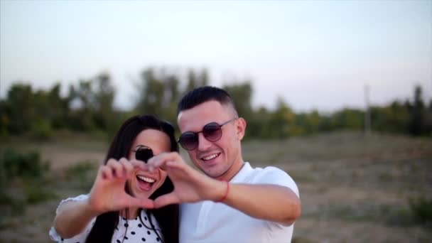 Hermosa feliz elegante alegre joven europea linda pareja en los brazos de los demás, hace de las manos de una idea romántica de amor en la forma de un corazón. Concepto de Amor . — Vídeos de Stock