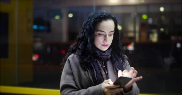 Beautiful Happy Young Woman in Brown Coat with Dark Blue Scarf and Long Dark Curly Hair Enjoys Coffee Busy with her Mobile Phone While Walking a City Street. Pretty Girl Messaging on the Smartphone 4K — Stock Video