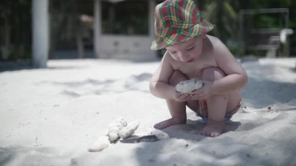 Joyeux garçon dans un chapeau jouant sur le sable . — Video