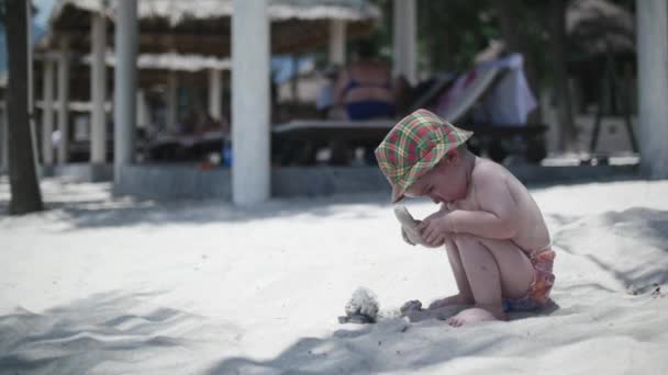 Glücklicher Junge mit Hut, der auf dem Sand spielt. — Stockvideo