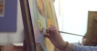 Genç güzel kadın sanatçı bir sanat stüdyosu, bir şövale arkasında oturan ve tuval üzerine resim mevcuttur. Çizim işlemi: sanatçılar sanat stüdyoda el sanat kız ile Canvas.4k bir fırça boyama