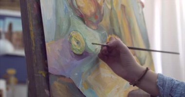 Genç güzel kadın sanatçı bir sanat stüdyosu, bir şövale arkasında oturan ve tuval üzerine resim mevcuttur. Çizim işlemi: sanatçılar sanat stüdyoda el sanat kız ile Canvas.4k bir fırça boyama