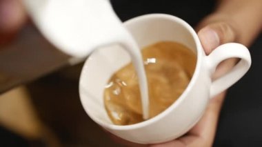 Akış süt bir fincan espresso, ağır çekim dökme. Yakın çekim. Stok görüntüleri.