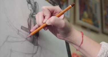 Genç güzel kadın sanatçı bir sanat stüdyosu, bir şövale arkasında oturan ve tuval üzerine resim mevcuttur. Çizim işlemi: sanatçılar sanat stüdyoda el sanat kız ile Canvas.4k bir fırça boyama