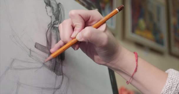 Jonge mooie vrouwelijke artiest is een Art Studio, zitten achter een ezel en schilderen op Canvas. Tekening proces: in het Art-Atelier van de kunstenaars Hand kunst meisje met een borstel schilderij op Canvas.4k — Stockvideo