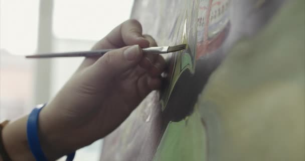Young Beautiful Female Artist è in uno studio d'arte, seduto dietro una anguilla e pittura su tela. Processo di disegno: nello studio d'arte degli artisti mano Art Girl con una pittura a pennello su tela.4K — Video Stock