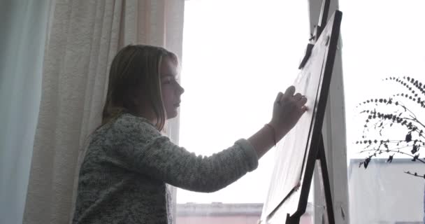 Joven artista femenina hermosa está en un estudio de arte, sentado detrás de un caballete y pintura sobre lienzo. Proceso de Dibujo: en el Estudio de Arte de la Mano de los Artistas Chica de Arte con Pincelada sobre Lienzo.4K — Vídeos de Stock