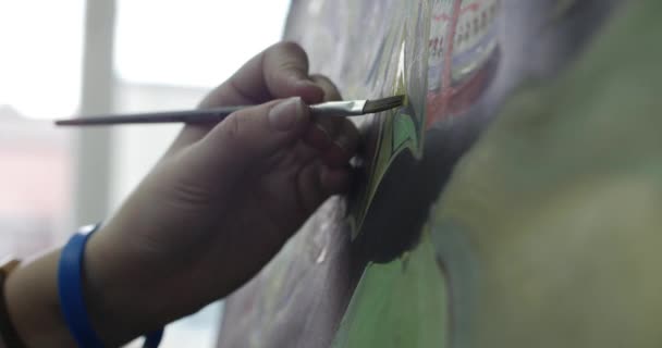 Jeune belle artiste féminine est dans un studio d'art, assis derrière un chevalet et peinture sur toile. Processus de dessin : dans l'atelier d'art des artistes Hand Art Girl with a Brush Painting on Canvas.4K — Video