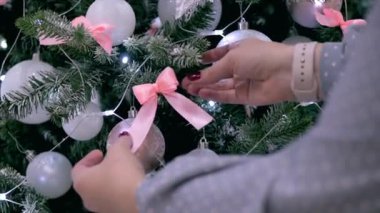 Bir kadının genç eller fiyonk Noel ağacı üzerinde yayılmış, şenlikli ışıkları ve Noel topları ile şenlikli Noel ağacı süslemeleri.