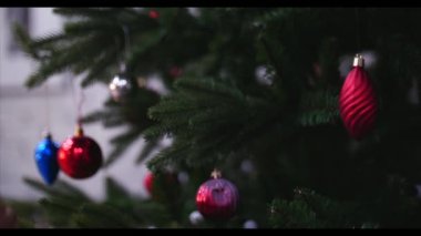 Noel süsler Noel ışıkları ile bir ağaç üzerinde asılı. Küçük bir kızın elleri yakın çekim bir Noel ağacı süsleyin. 4k