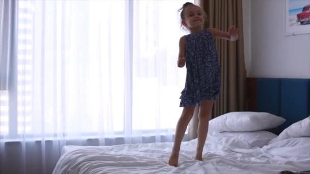 Happy little Caucasian girl jumping on the bed. Slow motion. — Stock Video