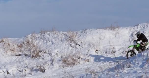 雪に覆われたモトクロス子供自転車ライダーのオートバイを追跡します。雪の上のライダー。バイク、モトクロス冬シーズンのレースのモトクロス ライダー。レーサー バイクに乗って冬の雪に覆われたモトクロス トラック. — ストック動画