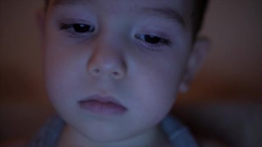 Onun gözlerinde ışık yansıması ile tablet Pc bakarak bir Childs'ın yüz gece resmi.