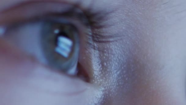 Tournage nocturne d'une jolie petite fille caucasienne Gros plan d'un visage d'enfant regardant une tablette PC avec un reflet de lutte et des photos dans ses yeux 