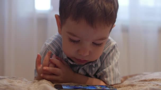 Cu, małe dziecko, mały chłopiec, stojąc przy łóżku oglądając telefon komórkowy, szczęśliwe dzieciństwo. — Wideo stockowe