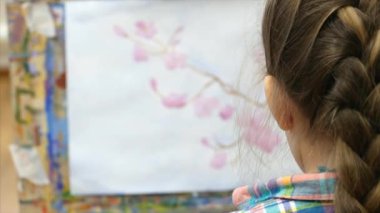 Genç Sevimli kadın sanatçı bir sanat stüdyosu, bir şövale arkasında oturan ve tuval üzerine resim mevcuttur. Çizim işlemi: sanatçılar sanat stüdyoda el sanat kız tuval üzerine bir fırça boyama.