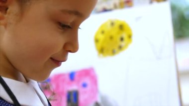 Genç Sevimli kadın sanatçı bir sanat stüdyosu, bir şövale arkasında oturan ve tuval üzerine resim mevcuttur. Çizim işlemi: sanatçılar sanat stüdyoda el sanat kız tuval üzerine bir fırça boyama.