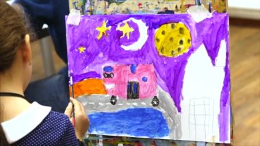 Genç Sevimli kadın sanatçı bir sanat stüdyosu, bir şövale arkasında oturan ve tuval üzerine resim mevcuttur. Çizim işlemi: sanatçılar sanat stüdyoda el sanat kız tuval üzerine bir fırça boyama.