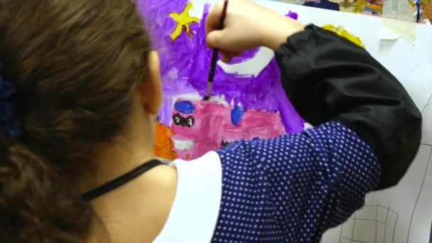 Joven artista femenina linda está en un estudio de arte, sentado detrás de un caballete y pintura sobre lienzo. Proceso de dibujo: en el estudio de arte de los artistas Hand Art Girl con un pincel Pintura sobre lienzo . — Vídeos de Stock