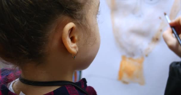Jeune artiste féminine mignonne est dans un studio d'art, assis derrière un chevalet et peinture sur toile. Processus de dessin : dans le studio d'art des artistes Hand Art Girl avec une peinture à la brosse sur toile . — Video