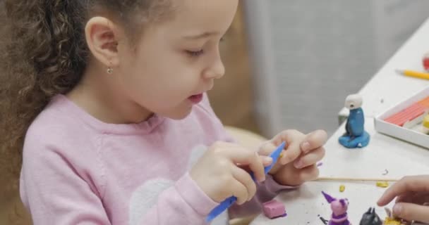 Симпатичные маленькие дети, сидящие за письменным столом, делают фигурки, отличные от тех, что сделаны из цветного пластилина для моделирования в детской. Развитие искусства моделирования у детей . — стоковое видео