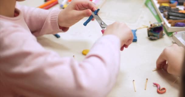Lindos niños pequeños sentados en el escritorio esculpe unas figuras diferentes de plastilina de modelado de colores en el vivero. Desarrollo del arte de modelar en niños . — Vídeos de Stock