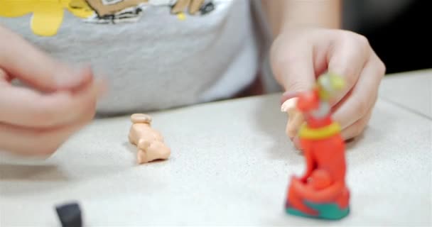 Des petits enfants mignons assis au bureau sculptent des figures différentes à partir de plastique de modélisation coloré dans la pépinière. Développement de l'art de la modélisation chez les enfants . — Video