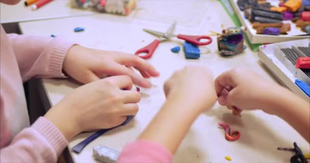 Lindos niños pequeños sentados en el escritorio esculpe unas figuras diferentes de plastilina de modelado de colores en el vivero. Desarrollo del arte de modelar en niños . — Vídeo de stock