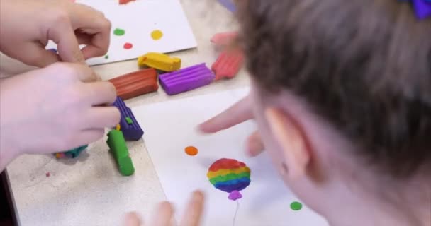 Lindos niños pequeños sentados en el escritorio esculpe unas figuras diferentes de plastilina de modelado de colores en el vivero. Desarrollo del arte de modelar en niños . — Vídeos de Stock