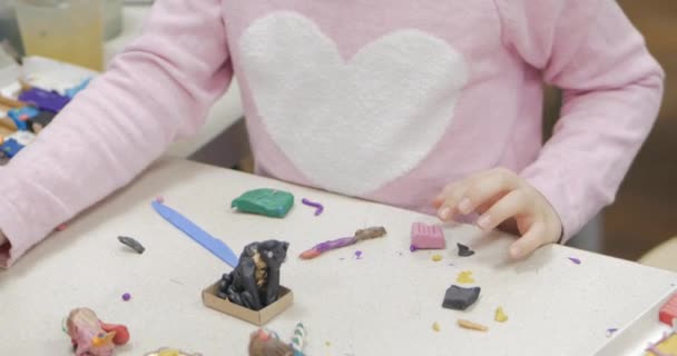 Söta små barn sitter vid skrivbordet skulpterar en olika siffror från gjord av färgade modellering Plastilina i barnkammaren. Utvecklingen av konsten att modellering i barn. — Stockvideo