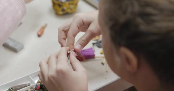 Leuke lieve kinderen zitten aan de balie beeldhouwt een verschillende figuurtjes uit gemaakt van gekleurde Modeling Plasticine in de kinderkamer. Ontwikkeling van de kunst van het modelleren in kinderen. — Stockvideo