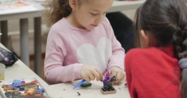 Sevimli küçük çocuklar masa başında oturan Sculpts farklı rakamları renkli modelleme hamuru odasında yapılmış. Modelleme çocuklarda sanatı gelişimi.