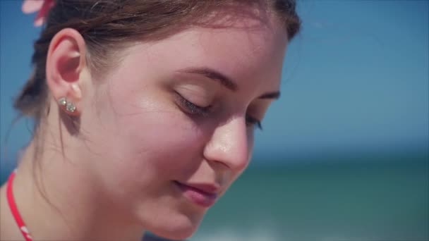 열 대 해변 클로즈업의 초상화에 유럽 아름 다운 귀여운 갈색 머리와 태양 유리 젊은 여자 또는 쾌활 한 소녀 카메라를 보고, 바람 머리 바람, 슬로우 모션. — 비디오