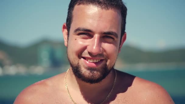 Close up ritratto giovane caucasico di bello bruna uomo un barba guardando in il fotocamera sorrisi, su blu cielo sfondo . — Video Stock
