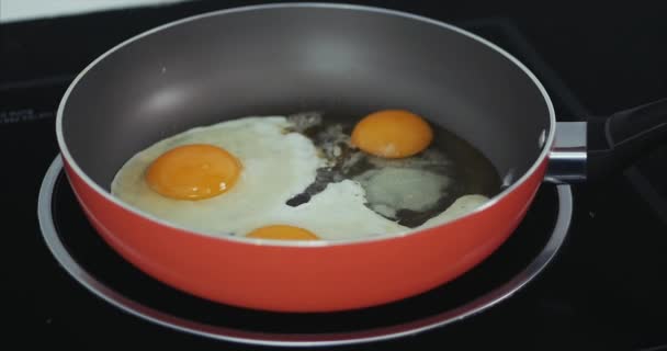 El chef prepara huevos fritos, cocina con mantequilla, sazonada con sal y pimienta negra y cebollas verdes en una cacerola roja pequeña. Concepto de alimentación saludable . — Vídeos de Stock