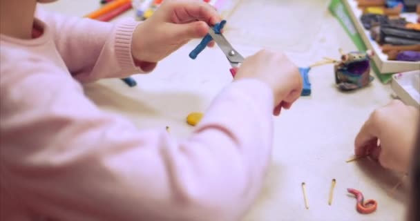 Leuke lieve kinderen zitten aan de balie beeldhouwt een verschillende figuurtjes uit gemaakt van gekleurde Modeling Plasticine in de kinderkamer. Ontwikkeling van de kunst van het modelleren in kinderen. — Stockvideo