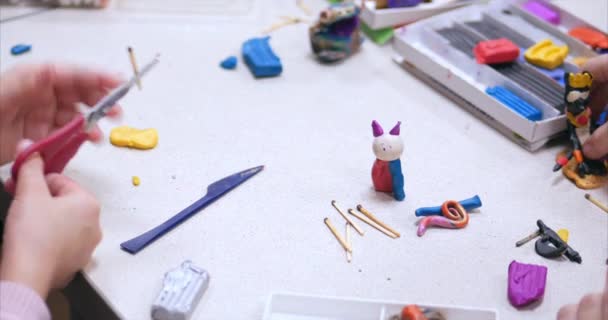 Leuke lieve kinderen zitten aan de balie beeldhouwt een verschillende figuurtjes uit gemaakt van gekleurde Modeling Plasticine in de kinderkamer. Ontwikkeling van de kunst van het modelleren in kinderen. — Stockvideo