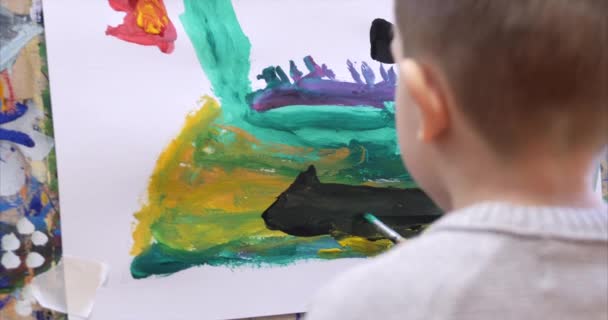 アーティストの若い手、小さな子アーティストは、ブラシでキャンバスを描画し、テーブルを座って、キャンバスに描画します。描画のプロセス: アーティストアートスタジオハンド赤ちゃんの女の子のキャンバスにスケッチ。ショットクローズアップ — ストック動画