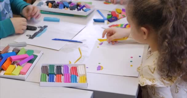 Aranyos kis gyermekek, ül a pult Sculpts különböző számadatai készült színes modellező gyurma a gyerekszobában. A művészet a modellezés gyerekek fejlesztése. — Stock videók