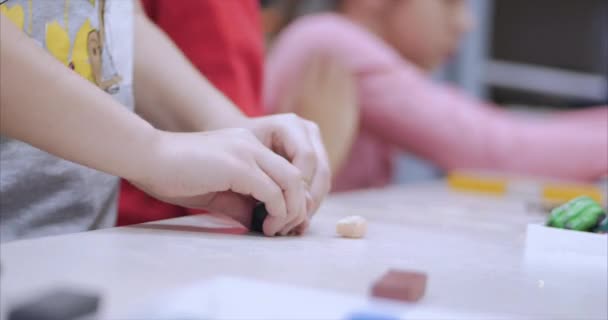 Söta små barn sitter vid skrivbordet skulpterar en olika siffror från gjord av färgade modellering Plastilina i barnkammaren. Utvecklingen av konsten att modellering i barn. — Stockvideo
