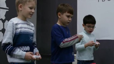 Çocuk turnuvasında, üç sevimli çocuk yüksek teknoloji oyunları oynamak, oyun joystick Ile robotlar kontrol, çocuk elleri yakın çekim. Çocuklar video oyunları oynuyor. 4k