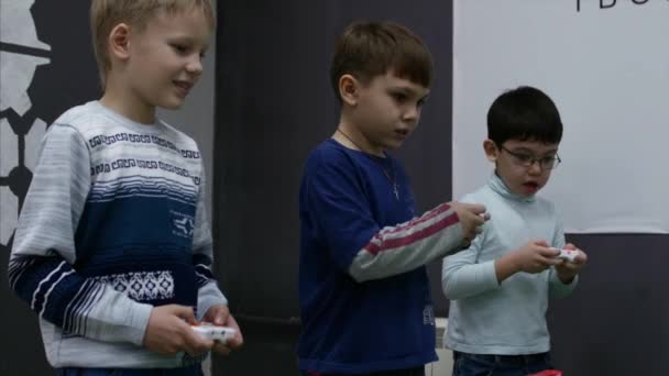 W turnieju Childrens, trzy cute dzieci grać High-Tech gry, kontrolowanie robotów z joysticki gry, zbliżenie dzieci ręce. Dzieci gry wideo. 4K — Wideo stockowe