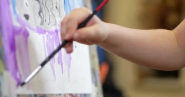 Sanatçının genç elleri, küçük kadın sanatçı fırça ile bir tuval boyar, bir masa oturan ve tuval üzerine çizin. Çizim süreci: sanatçılar sanat stüdyosu el bebek kız Canvas. Shot üzerinde çizim