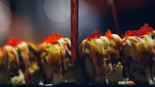 Mão de mulher jovem com paus leva Sushi. Conceito de chinês varas Sushi Rolls em uma placa escura . — Vídeo de Stock